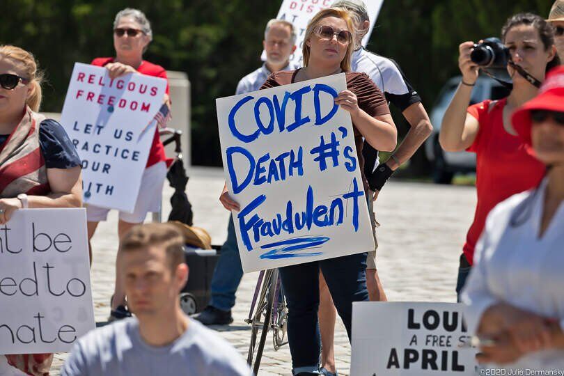 Mujer con un cartel de negación de la Covid-19 en una protesta de "Fin del confinamiento" en Baton Rouge, Louisiana, el 25 de abril. Julie Dermansky